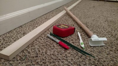 DIY Horse Measuring Stick Supplies Wood board, wooden dowel, PVC saddle tee, tape measure, markers, and zip ties laid out for a DIY horse measuring stick