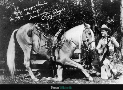 Trigger and Roy Rogers Signed Publicity Photo Signed publicity photo of Roy Rogers playing guitar beside his famous palomino horse Trigger